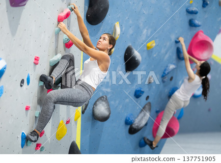 Young woman practicing rock climbing on climbing wall 137751905