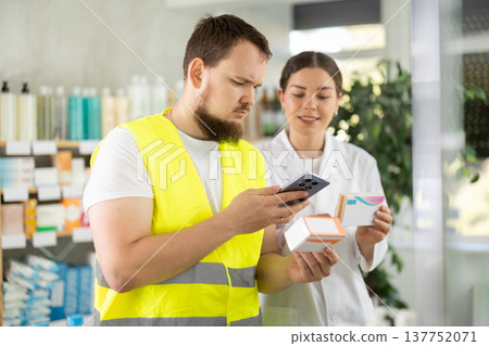 Laborer man builder in pharmacy scans QR code on pills box, pharmacist offer help for customer Laborer man builder in pharmacy scans QR code on pills box, pharmacist offer help for customer 137752071