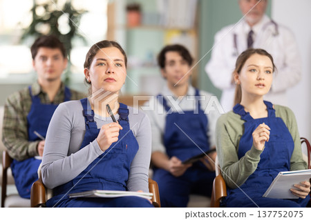 Young female student worker listening to lecture with medical professor in background Young female student worker listening to lecture with medical professor in background 137752075