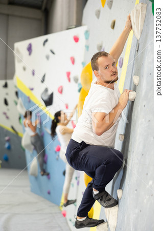 Young man practicing rock climbing on climbing wall 137752083