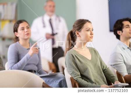 Female student listening to a lecture against the background of a doctor 137752103