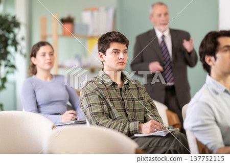 Young guy watching presentation with a teacher standing in background Young guy watching presentation with a teacher standing in background 137752115
