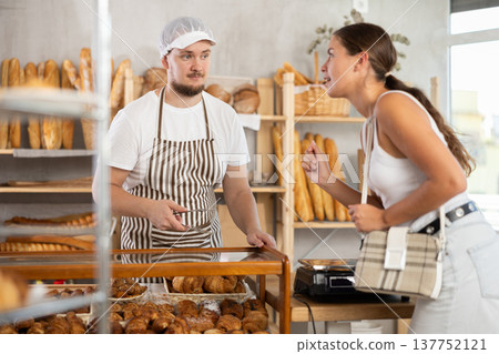Young man seller serves girl buying fresh croissants in bakery Young man seller serves girl buying fresh croissants in bakery 137752121