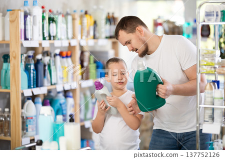 Young man and boy choosing detergent in store Young man and boy choosing detergent in store 137752126