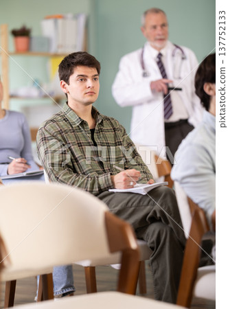 student guy listens to a lecture against the background of a doctor teacher 137752133