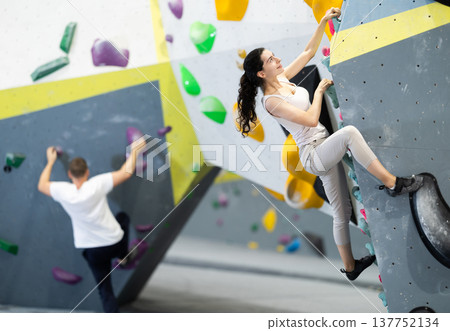 Young woman doing rock climbing on climbing wall 137752134