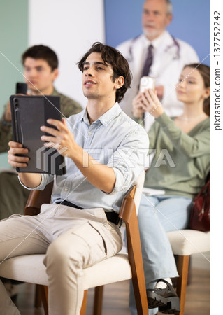 Male student scanning qr code in lecture hall 137752242