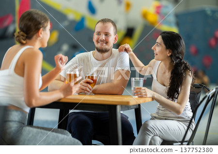 Man and two women talk at table on climbing wall Man and two women talk at table on climbing wall 137752380