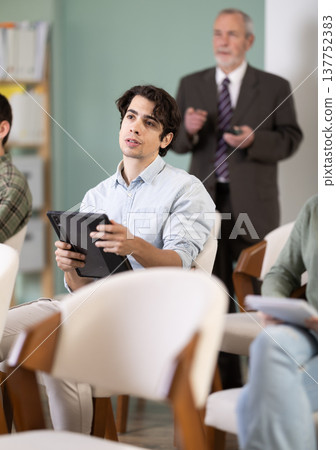 Guy student listens to a lecture, on background of the senior teacher Guy student listens to a lecture, on background of the senior teacher 137752383