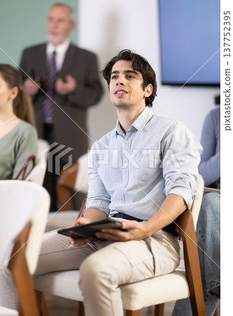 Young guy watching presentation with a teacher standing in background Young guy watching presentation with a teacher standing in background 137752395