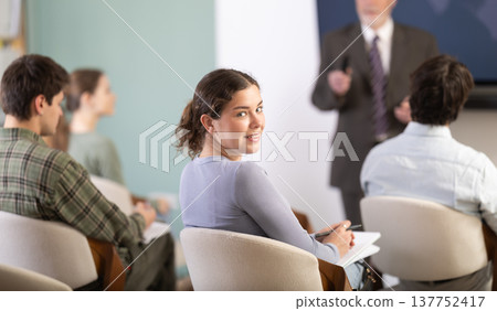 Young girl watching presentation with a teacher standing in background Young girl watching presentation with a teacher standing in background 137752417
