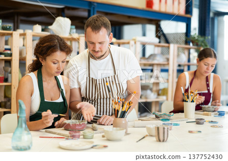 Male potter explains to students how to shape clay to make beautiful ceramic dishes 137752430