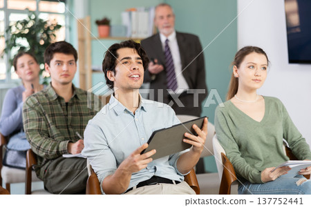 Students are listening to a lecture, and the teacher is standing in the background Students are listening to a lecture, and the teacher is standing in the background 137752441