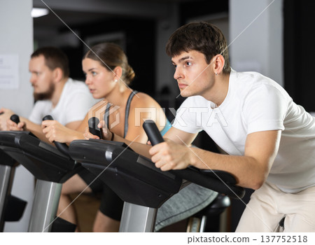 Guy is exercising on an exercise bike Guy is exercising on an exercise bike 137752518