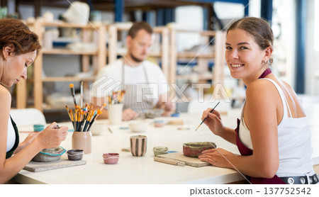 Three craftsperson are busy painting clay products Three craftsperson are busy painting clay products 137752542