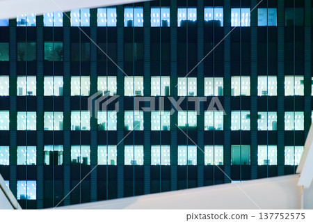 Tokyo, Japan, panoramic view of the facade of an office building at night with lights on in most windows of offices where people work 137752575