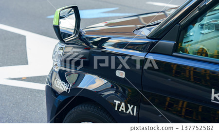 Tokyo, Japan - Oct 14 2024, Close-up view of a part of the hood, side mirror of a black cab, with the inscription "taxi", in the Ginza district, Tokyo, Japan Tokyo, Japan - Oct 14 2024, Close-up view of a part of the hood, side mirror of a black cab, with the inscription "taxi", in the Ginza district, Tokyo, Japan 137752582