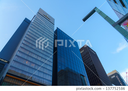 Tokyo, Japan - Oct 14 2024,  A panoramic view from below of the glass facades of skyscrapers in the Ginza district, against the backdrop of a clear blue sky, in the evening, Tokyo, Japan 137752586
