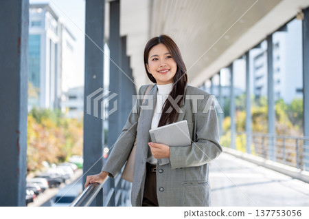 Pretty asian woman student office worker carrying tablet standing and holding railing on footbridge. Pretty asian woman student office worker carrying tablet standing and holding railing on footbridge. 137753056
