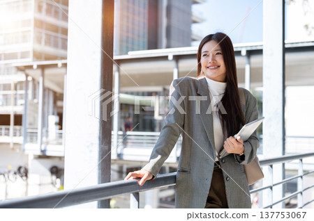 Pretty asian woman student office worker holding tablet standing at railing on bridge with cityscape Pretty asian woman student office worker holding tablet standing at railing on bridge with cityscape 137753067