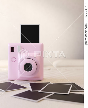 Pink square instant camera and a pile of black film photos on blanket or sheet on bed in white room. Pink square instant camera and a pile of black film photos on blanket or sheet on bed in white room. 137753149