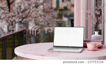 White screen laptop with coffee and books on round marble table at balcony aside a pink flower tree. White screen laptop with coffee and books on round marble table at balcony aside a pink flower tree. 137753156