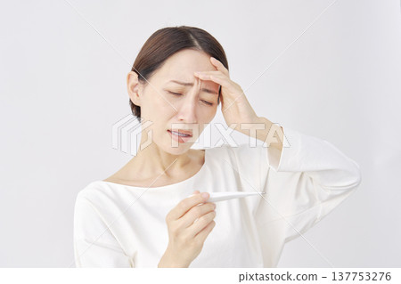 Woman measuring temperature with a thermometer on a white background 137753276