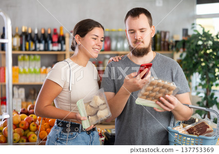 Couple purchaser scanning QR code or barcode of mushrooms in supermarket 137753369