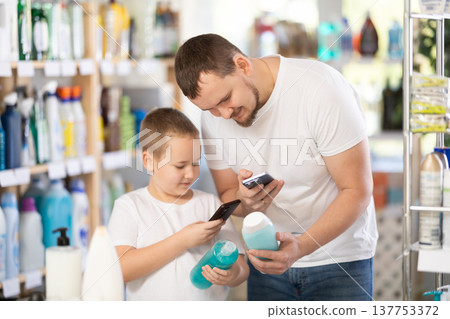 Man and boy scanning qr code for shampoo or shower gel Man and boy scanning qr code for shampoo or shower gel 137753372