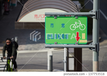 A sign for a municipal bicycle parking lot in Nagoya city, and a man riding a bicycle. A sign for a municipal bicycle parking lot in Nagoya city, and a man riding a bicycle. 137753518