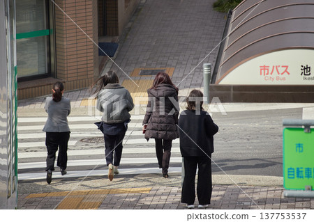 The scene of young female office workers waiting at a crosswalk in a busy city center during the daytime in winter. The scene of young female office workers waiting at a crosswalk in a busy city center during the daytime in winter. 137753537