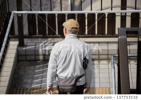 A middle-aged man descending the stairs of a pedestrian overpass in a city on a winter morning. 137753538