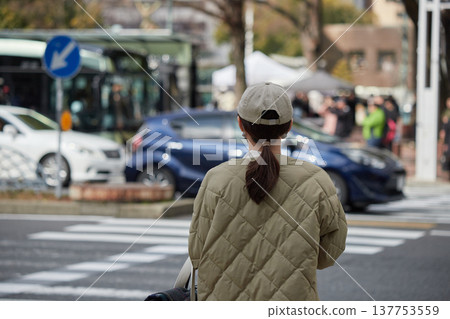 冬日的白天，一位年輕的家庭主婦在名古屋市中心的人行道前等候。 137753559