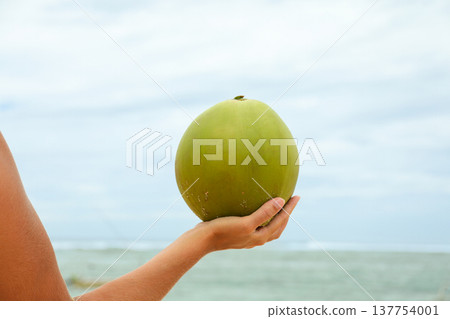 Person holds a coconut at the beach in Bali 137754001