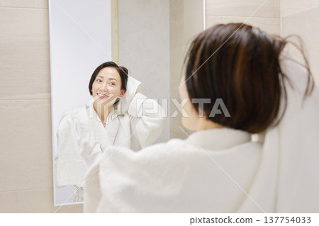 A woman wiping her wet hair with a bath towel after taking a bath A woman wiping her wet hair with a bath towel after taking a bath 137754033