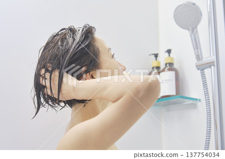 Woman washing her hair in the bathroom 137754034