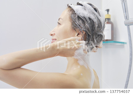 Woman washing her hair in the bathroom 137754037