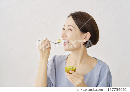 A woman eating kiwi fruit in the living room A woman eating kiwi fruit in the living room 137754061