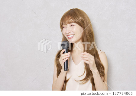 中年婦女手持麥克風唱歌，肖像，灰色背景 137754065