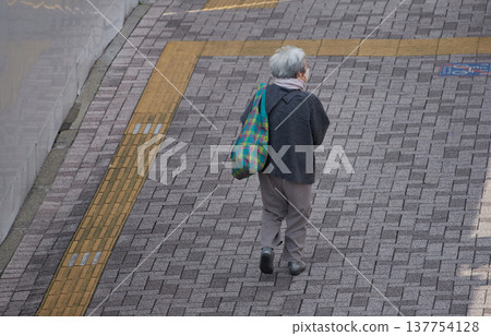 冬日清晨，從高角度拍攝的幾位老年女性購物者走在城市街道上。 137754128
