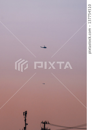 夕陽西下，一架直升機和一根電線桿在空中飛翔。 137754510