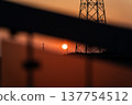 Sunset and transmission towers visible from a pedestrian overpass in the city. Sunset and transmission towers visible from a pedestrian overpass in the city. 137754512