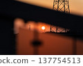 Sunset and transmission towers visible from a pedestrian overpass in the city. Sunset and transmission towers visible from a pedestrian overpass in the city. 137754513