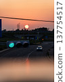 Sunset and transmission towers visible from a pedestrian overpass in the city. Sunset and transmission towers visible from a pedestrian overpass in the city. 137754517