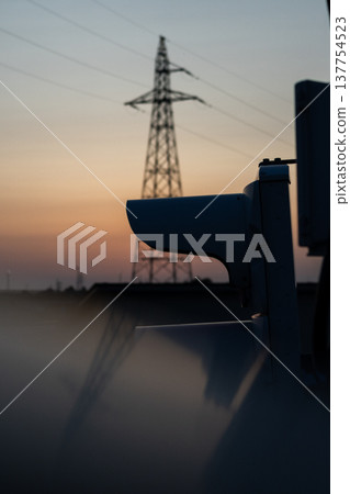 Sunset and transmission towers visible from a pedestrian overpass in the city. Sunset and transmission towers visible from a pedestrian overpass in the city. 137754523