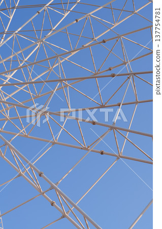 摩天輪中心軸和鋼架結構的特寫鏡頭,背景是藍天。 摩天輪中心軸和鋼架結構的特寫鏡頭,背景是藍天。 137754781