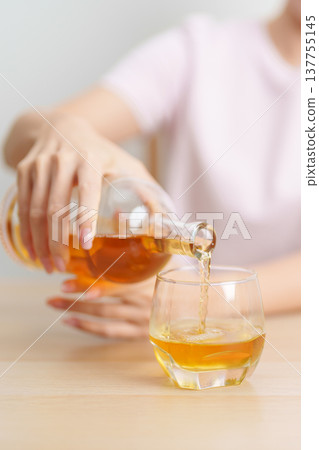woman pour whiskey into a glass on table, suffering from alcohol addiction, alcoholism concept. depicting emotional distress, depression, substance abuse problem, unhealthy lifestyle and mental health 137755145