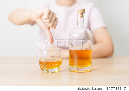 woman show thumb down hand gesture to refuse a glass of whisky, Healthy man say no to alcohol drink, stop alcoholism and addiction concept. Responsible man reject a drink before driving and quit booze 137755147
