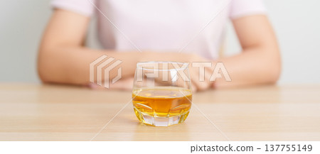 woman with glass of whiskey on table, suffering from alcohol addiction and alcoholism concept. depicting emotional distress, depression, substance abuse problem, unhealthy lifestyle and mental health 137755149