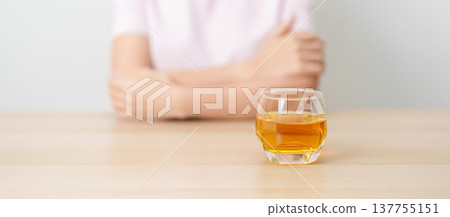 woman with glass of whiskey on table, suffering from alcohol addiction and alcoholism concept. depicting emotional distress, depression, substance abuse problem, unhealthy lifestyle and mental health 137755151